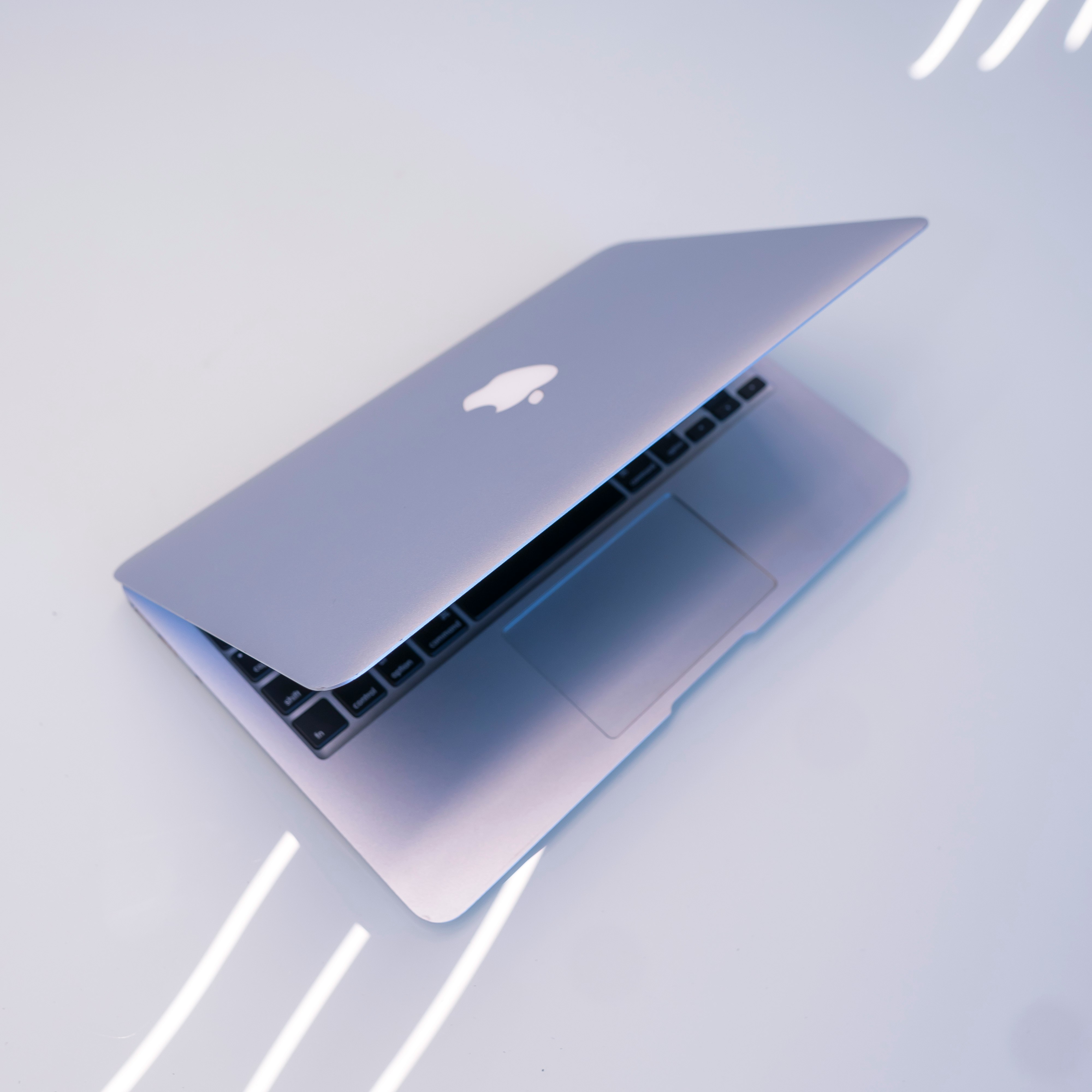 silver macbook on white table